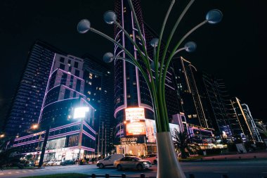 Batumi, Georgia, 7 Ekim 2025. Aydınlatılmış modern binanın su yüzeyine yansıyan gece görüşü. Yüksek kalite fotoğraf
