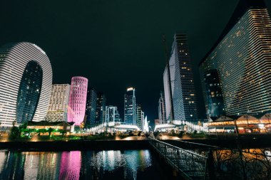 Batumi, Georgia, 7 Ekim 2025. Aydınlatılmış modern binanın su yüzeyine yansıyan gece görüşü. Yüksek kalite fotoğraf