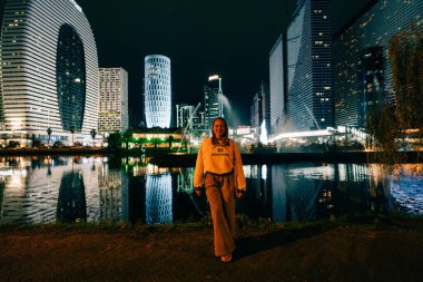 Batumi, Georgia, 7 Ekim 2025. Aydınlatılmış modern binanın su yüzeyine yansıyan gece görüşü. Yüksek kalite fotoğraf