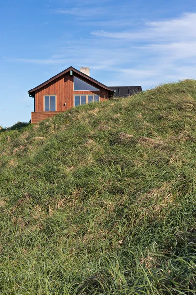 Παραδοσιακό δανική σπίτι μέσα στον αμμόλοφο της άμμου με το γαλάζιο του ουρανού και το πράσινο γρασίδι — Φωτογραφία Αρχείου