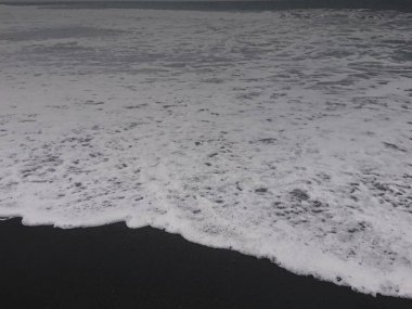 Dalgaların ve kumsaldaki kum manzaralarının fotoğrafları.