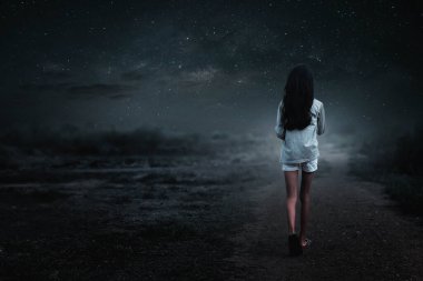 Yalnız kız gecenin bir yarısı toprak yolda yürüyor.