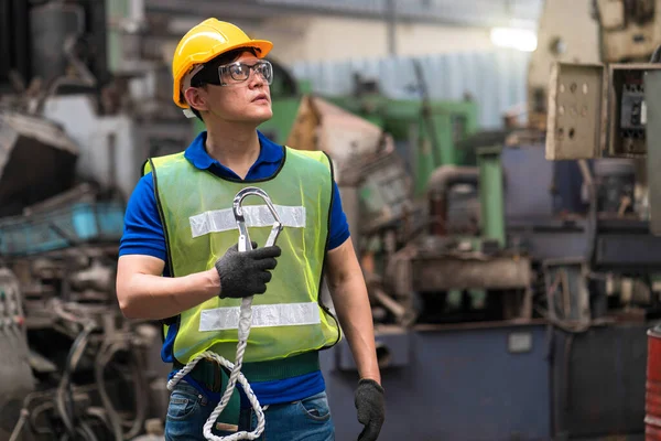 Industrial mechanics are holding sling hooks in an industrial plant.