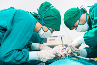 Doktorlar koruyucu eldiven takıyor, modern tıbbi ekipmanlarla donatılmış ameliyathanedeki hastaları muayene ediyor ve tedavi ediyorlar..