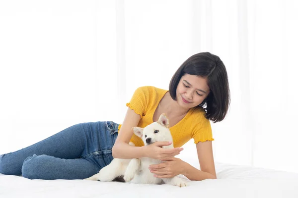 白い寝室のベッドで北海道犬や柴犬を抱きしめる少女 — ストック写真