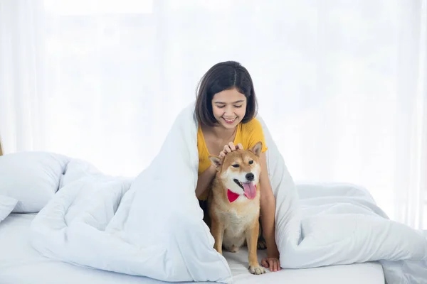 芝犬とベッドの上に座っているアジアの女性 — ストック写真