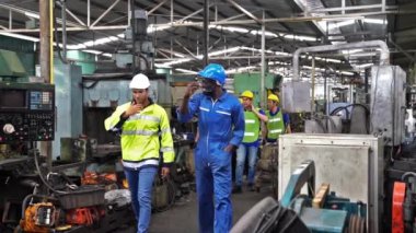 Mühendisler ve çalışanlar teneffüste fabrikaya girerler. Mühendisler ve sanayi işçileri büyük makineler üzerinde çalışıyorlar..