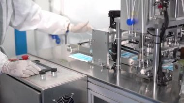 Maske fabrikasındaki işçiler modern makinelerin üretimini kontrol ediyorlar..