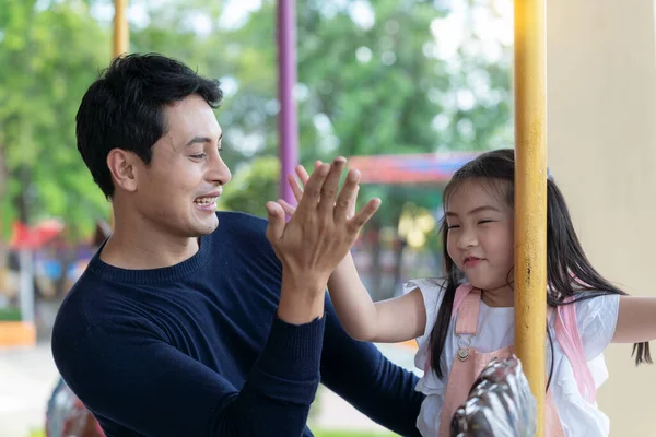 Lunaparktaki aile. Baba ve oğlu lunaparkta gülüyorlar. Atlıkarıncada oynayan çocuklu babamız..