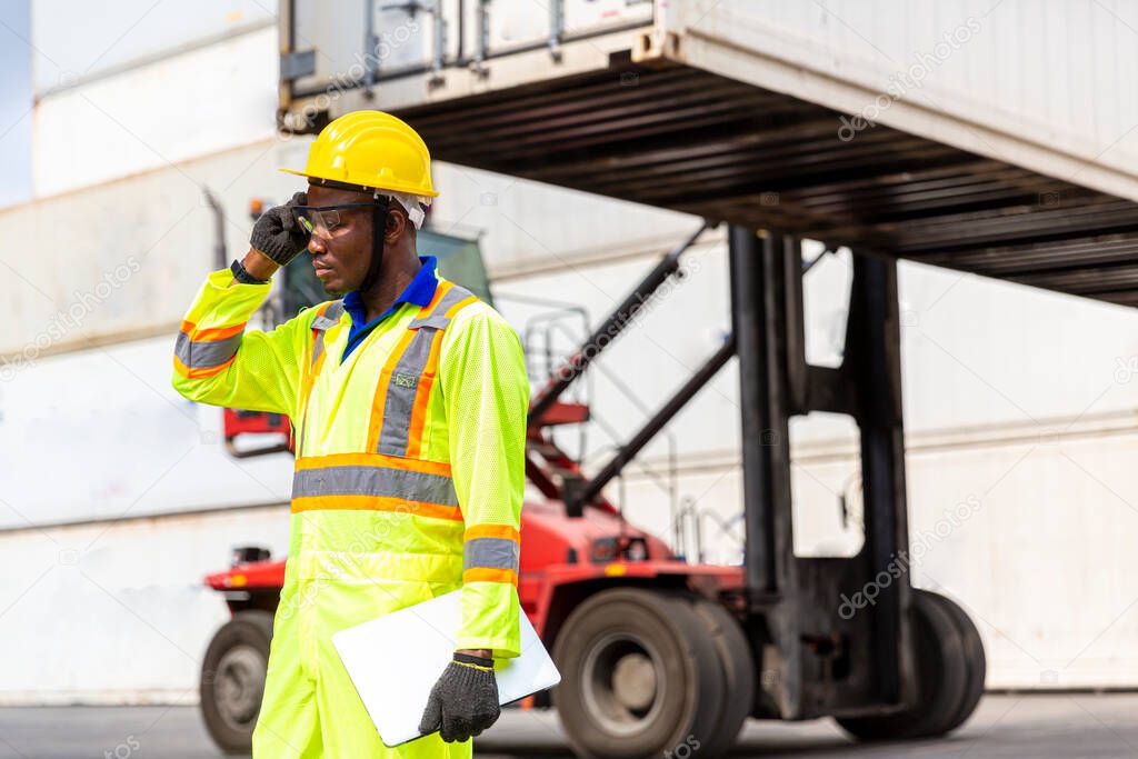 Foreman using mobile phone and laptop in the port of loading goods. Foreman on Forklifts in the Industrial Container Cargo freight ship.