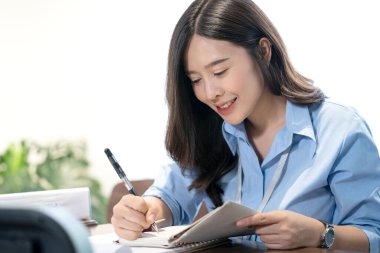 Çalışanlar ofiste notlar tutuyorlar. Masada gülümseyen Asyalı iş kadını..
