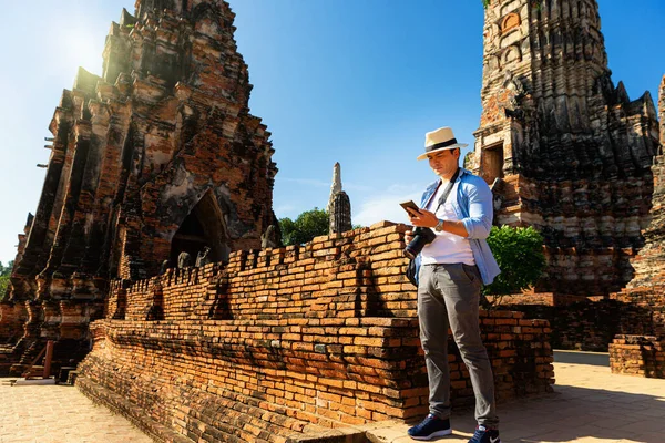 Travelers traveling to Asia. Foreign tourists traveling in the old city of Ayutthaya, Thailand. Young man visiting Ayutthaya attractions and landmarks in Thailand.