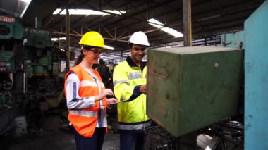 Fabrikada endüstriyel makineler üzerinde çalışan iki mühendis. Fabrikadaki endüstriyel makinelerde çalışan bir mühendis..