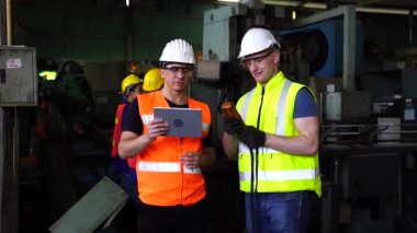 Fabrikadaki İşçi İşletme Makineleri. Mühendisler ve teknisyenler tabletle makinenin çalışmasını kontrol ediyorlar..