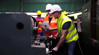 Makinenin önünde duran İngiliz anahtarı ve tableti tutan tamirci. Makine kontrol panelinde fabrika işçisi. Fabrika atölyesinde çalışan değirmen makinesi operatörü.