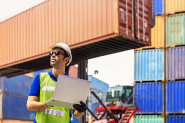 Foreman ya da Operator dizüstü bilgisayarlı konteynırların taşınmasını emrediyor. Foreman, sanayi konteynırı yük gemisindeki forkliftleri dört gözle bekliyor..