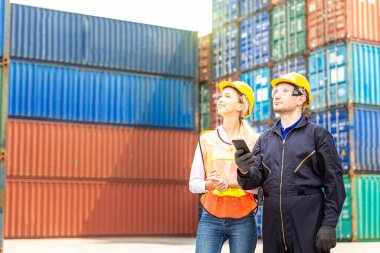 Foreman yükleme limanında cep telefonu kullanıyor. Foreman kontrol, ithalat için kargo gemisinden konteynır kutuları yüklüyor..