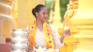Myanmar kadınları bir tapınakta çiçek tutuyorlar. Burma geleneksel elbiseli Güneydoğu Asyalı genç kızlar Budist tapınağını ziyaret ediyorlar.
