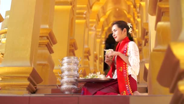 ミャンマーの女性は手に花を持っている 東南アジアの若いです女の子とともに仏教寺院を訪れるビルマの伝統的なドレス — ストック動画