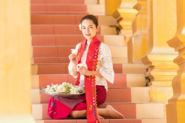Myanmar kadınları bir tapınakta çiçek tutuyorlar. Burma geleneksel elbiseli Güneydoğu Asyalı genç kızlar Budist tapınağını ziyaret ediyorlar.