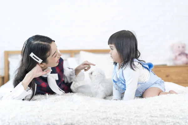 2人の若いアジア人女性が犬とベッドにいた マルタの子犬は女の子とベッドで白い毛皮を持っています — ストック写真