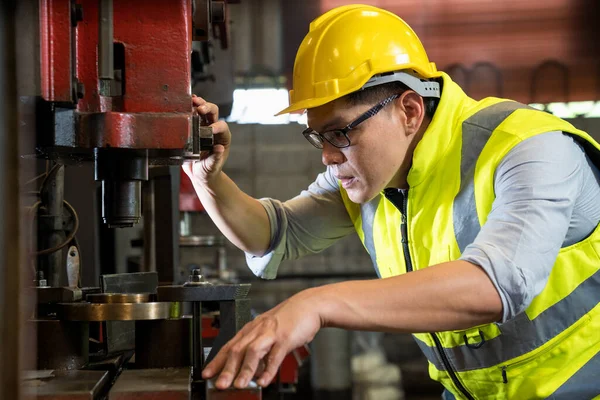 Manufacturing worker. Asian mechanical engineer operating industrial lathe machine.