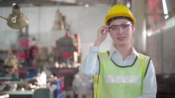 製造労働者 若い女性労働者は 工場のワークショップで機械を見てタブレットとハード帽子と保護ガラスを身に着けている — ストック動画