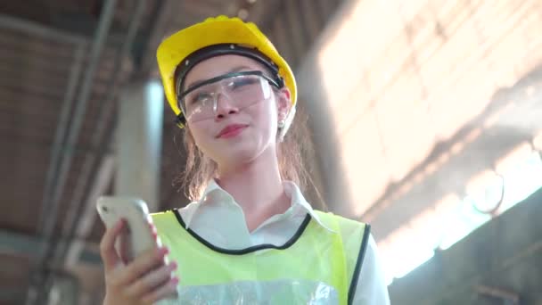 在工作中使用移动电话的制造业工人 亚洲工人控制着这项工作 工程师使用手机 智能工程通过电话交谈 — 图库视频影像