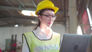 Fabrikada bilgisayar laptopu kullanan bir imalatçı. İşi kontrol eden Asyalı işçi.