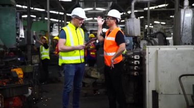 Fabrikada bilgisayar tableti kullanan bir imalatçı. İşi kontrol eden Asyalı işçi. Makine mühendisi endüstriyel torna makinesini çalıştırıyor..