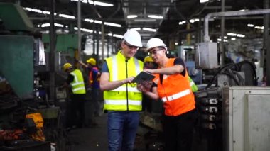 Fabrikada bilgisayar tableti kullanan bir imalatçı. İşi kontrol eden Asyalı işçi. Makine mühendisi endüstriyel torna makinesini çalıştırıyor..