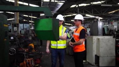 Fabrika atölyesinde otomatik robot makinelerinin ürünlerini üretmek için güvenlik şapkası komutu bilgisayarı takan işçiler.