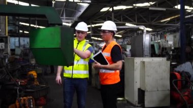 Fabrika atölyesinde otomatik robot makinelerinin ürünlerini üretmek için güvenlik şapkası komutu bilgisayarı takan işçiler.