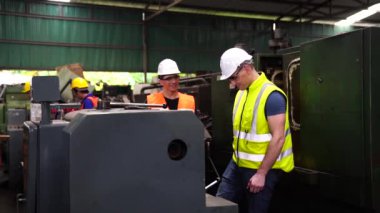 Fabrikada güvenlik şapkası takan işçiler. Mühendislik fabrikadaki makine ayarlarına bakıyor..