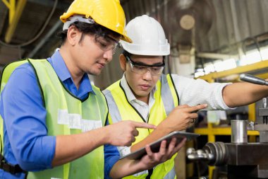 Mühendisler ve yetenekli teknisyenler makineleri koruyor. Profesyonel teknisyenler sanayi tesislerinde çalışmayı kontrol etmek için bir tablet tutuyorlar..