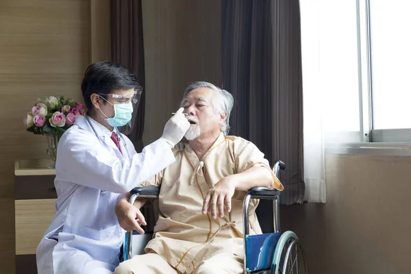 Doctors are testing the virus from elderly people. A doctor in protective clothing is testing a patient's virus in a hospital examination room..
