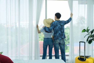 Genç Asyalı erkek ve kadınlar yolculuklarına mutlu bir şekilde hazırlanıyorlar. Genç çift pencereden dışarı bakarak dinleniyor..