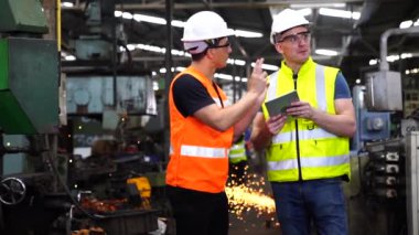 Teknisyenler endüstriyel makineler üzerinde çalışıyorlar. Fabrika atölyesinde makine ekipmanı kullanan bir grup işçi..