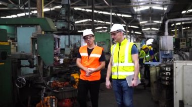 Teknisyenler endüstriyel makineler üzerinde çalışıyorlar. Fabrika atölyesinde makine ekipmanı kullanan bir grup işçi..