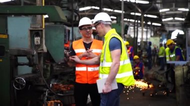 Teknisyenler endüstriyel makineler üzerinde çalışıyorlar. Fabrika atölyesinde makine ekipmanı kullanan bir grup işçi..