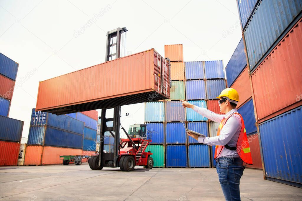 Foreman or Operator Ordering of moving containers with laptop computer. Foreman looking forward on Forklifts in the Industrial Container Cargo freight ship.