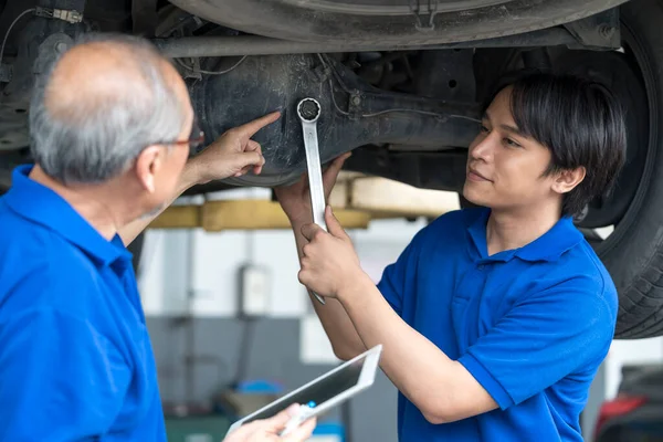 Car repairs. Auto services and Small business concepts. Asian business owners are recommending car repairs to auto mechanics.