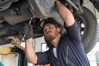 Otomobil servisi ve küçük işletme kavramları. Bir araba motorunu tamir etmek için İngiliz anahtarını kullanan otomatik tamirci elleri.