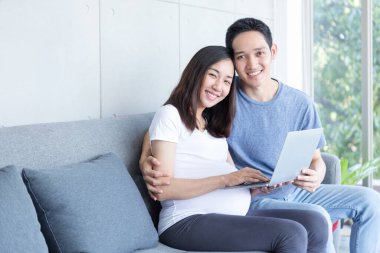 Bekleyen bir anne ve baba oturma odasında dizüstü bilgisayarlarıyla oturuyorlar..