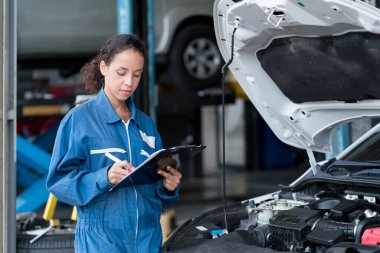 Servis onarım konsepti. Atölyede pano kontrol sistemi olan tamirci kadın. Tamirci kadın garajda araba tamir ediyor..