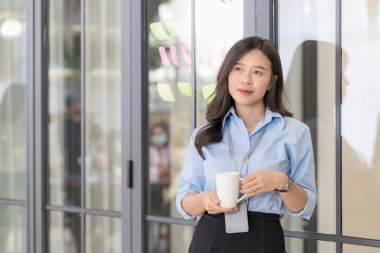 İşçi kadın ofiste sıcak kahve fincanlarıyla eğleniyor. Güzel genç iş kadını ofiste kahve içiyor..