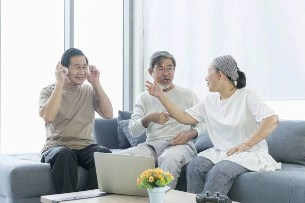 Happy time together. Two Mature man and one woman sitting at window. Retired men and women Listen to music in the living room.