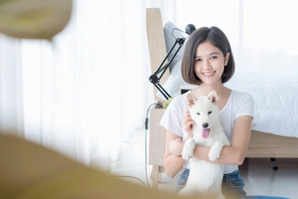 寝室に白い柴犬の子犬を抱えている若いアジア人女性 女の子と北海道犬 — ストック写真