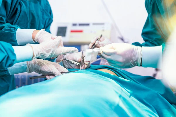 Doctors put together surgical gowns. Surgeon is operating a patient in an operating in a hospital