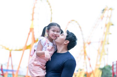 Baba ve kızı lunaparkta oynuyorlar. Lunaparkta hız trenine binen aile